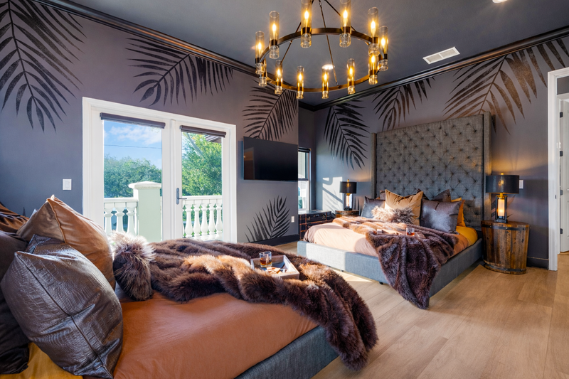 "Modern luxury bedroom at Gaspar's Estate Tampa with custom palm mural and two queen beds.