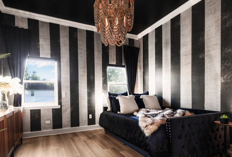 Calypso Suite at Gaspar's Estate Tampa featuring black and white striped walls, a beaded chandelier, and a black trundle aybed.