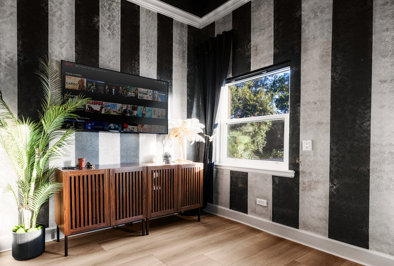 Large wall-mounted Smart TV and wooden slat credenza in the Calypso Suite at Gaspar's Luxury Estate, Tampa.