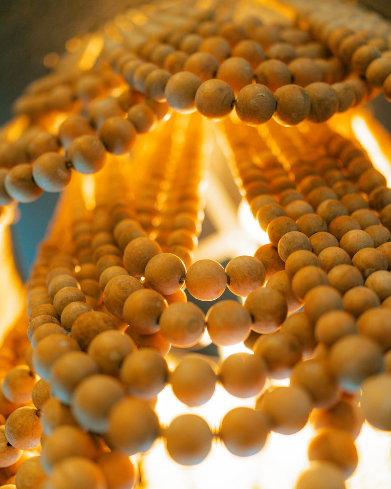 Close-up of the warm wood-beaded chandelier in the Calypso Suite at Gaspar's Luxury Estate, Tampa.