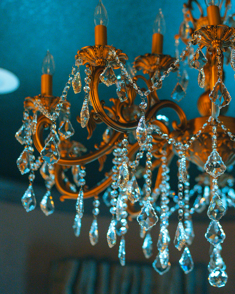 Ornate gold chandelier with teardrop crystal accents in the Gaspar's Quarters suite at Gaspar's Luxury Estate, Tampa.
