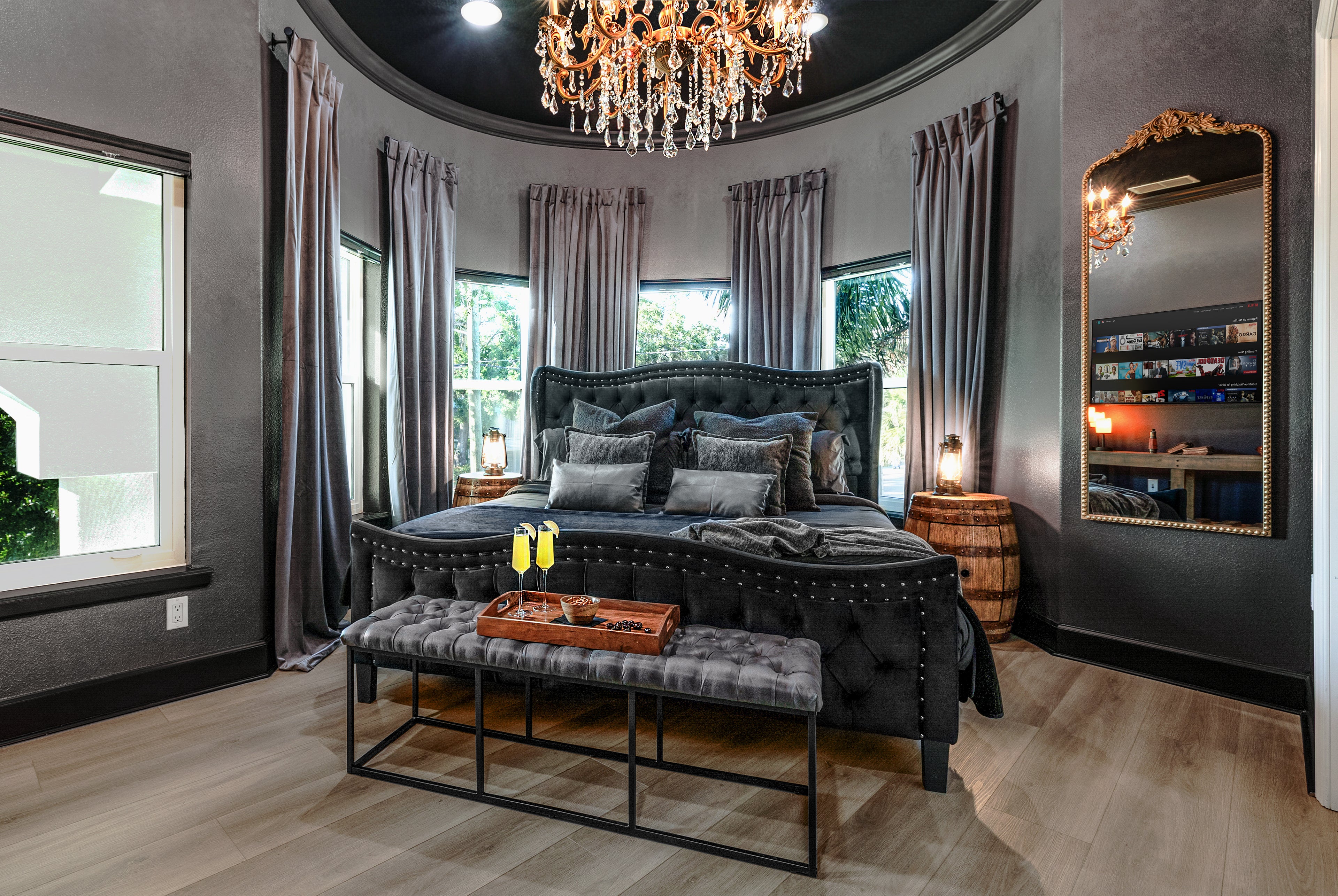 Gaspar’s Quarters king suite in Tampa with a curved turret wall, gold crystal chandelier, and velvet tufted bed.