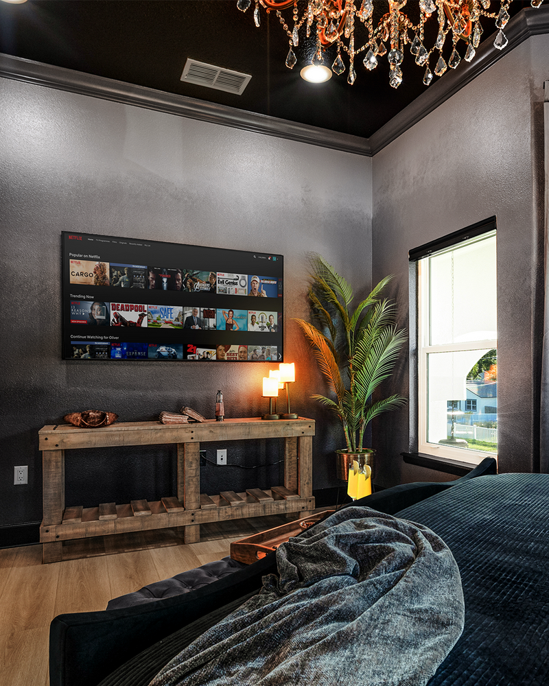 Wall-mounted Smart TV and rustic wood credenza in the Gaspar's Quarters suite at Gaspar's Estate Tampa.
